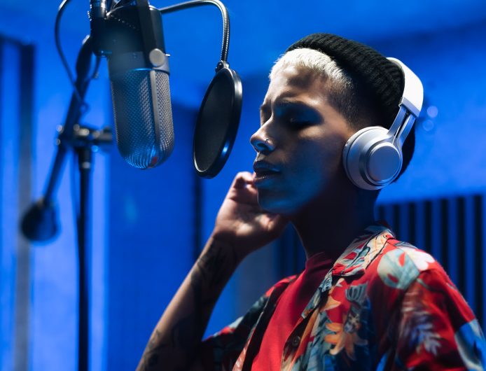 Young female singer recording a new song album inside music production studio